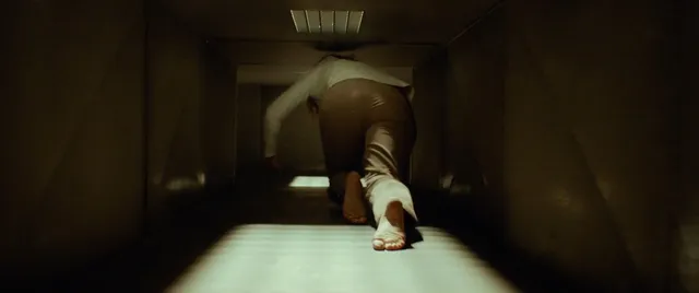 Maika Monroe showing a bare foot in a dimly lit scene.