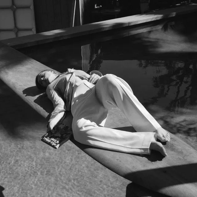 Chloë Grace Moretz lying barefoot in sunlight wearing a white outfit.
