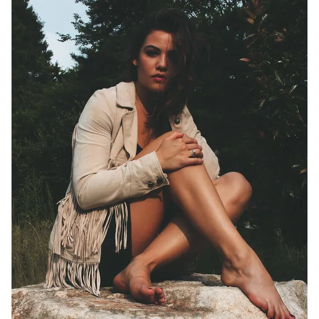 Danielle Campbell sitting on rocks outdoors during a portrait shoot.