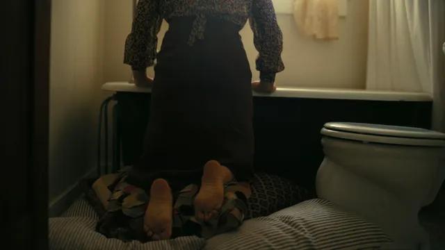 Florence Pugh a screen scene with bare soles visible beside a bathtub.