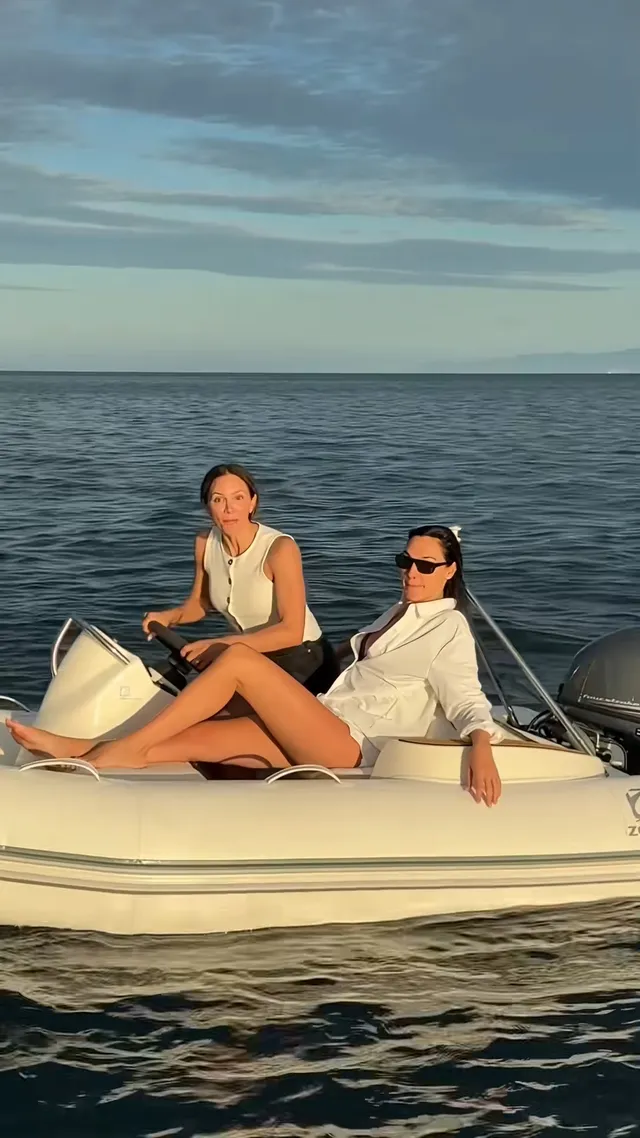 Gal Gadot sitting barefoot beside another woman on a boat.