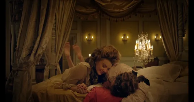 Natalie Dormer sitting beside another performer in a period screen scene.
