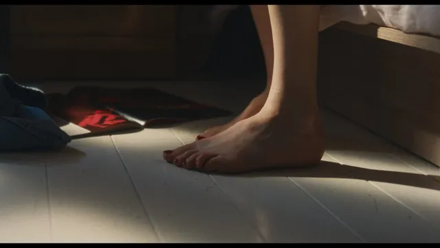 Sarah Pidgeon shown standing barefoot on a wooden floor.