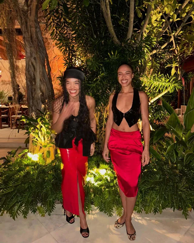 Tessa Thompson posing with a guest in a red skirt.