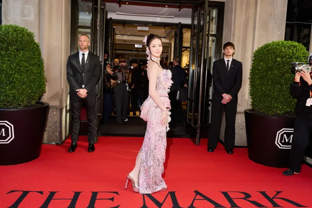 Jisoo wearing heels beneath a long patterned pink gown on a red carpet.