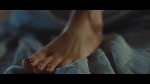 Adèle Exarchopoulos resting a bare foot on bedding in a screen scene.