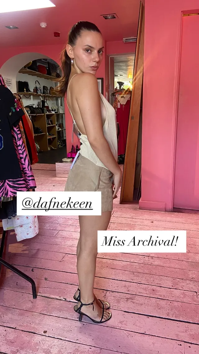 Dafne Keen posing in a pale dress and heels in a pink room.