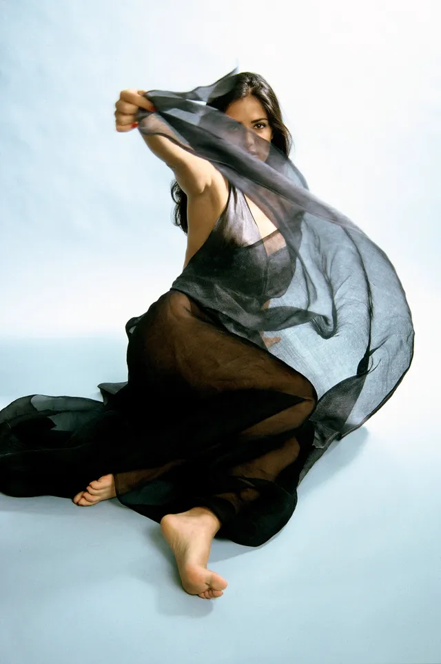 Salma Hayek posing on the floor in a flowing grey dress.