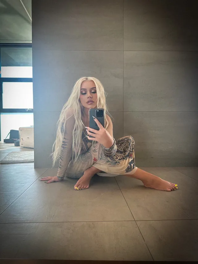Christina Aguilera sitting barefoot for a mirror photograph.