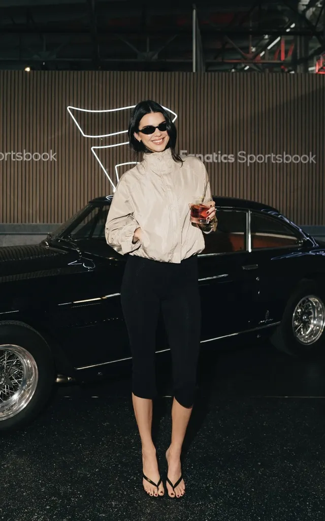 Kendall Jenner wearing black heels beside a black car.