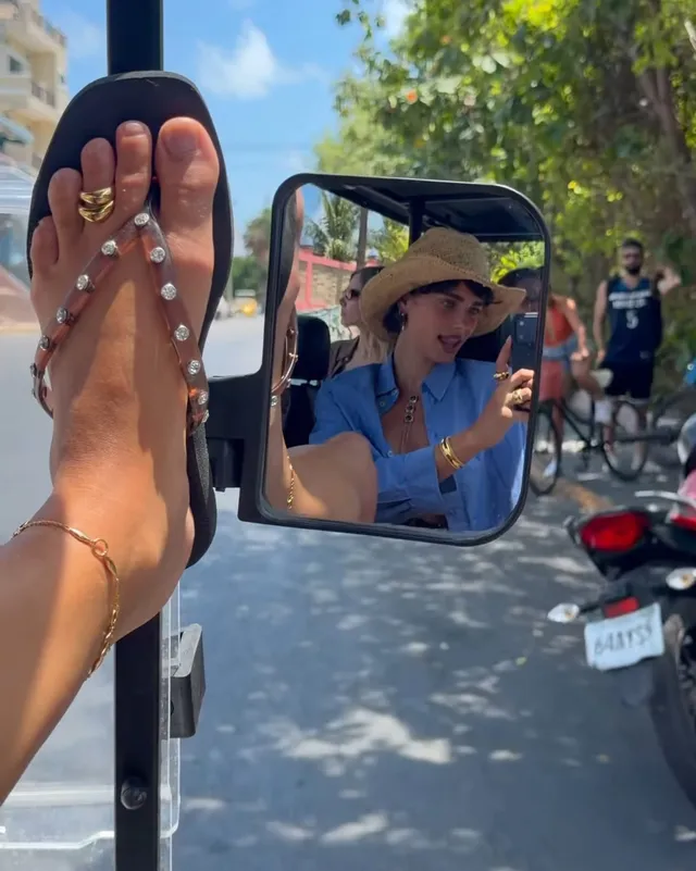 Taylor Hill showing jewelled flat sandals beside a vehicle mirror.