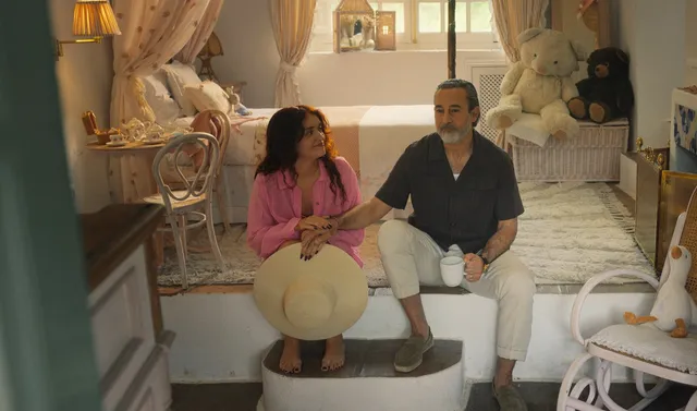 Olivia Cooke sitting beside a man in a furnished room scene.