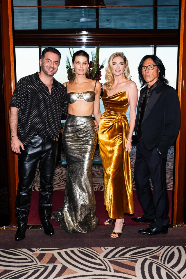 Kate Upton posing with three people wearing a gold dress and heels.