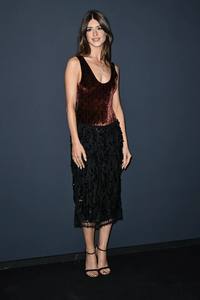 Daisy Edgar-Jones posing before an event backdrop in a black lace skirt.