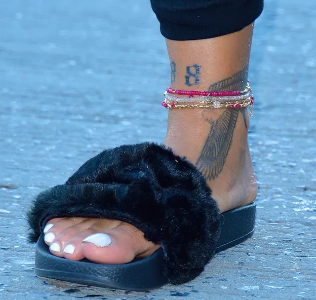 Rihanna showing a dark fur slide sandal in a close up.