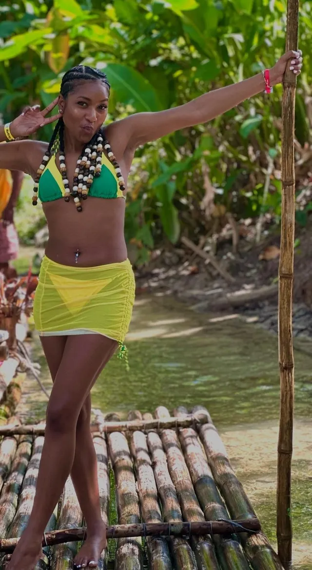 Carlacia Grant posing on a raft in a bikini top and yellow wrap skirt.