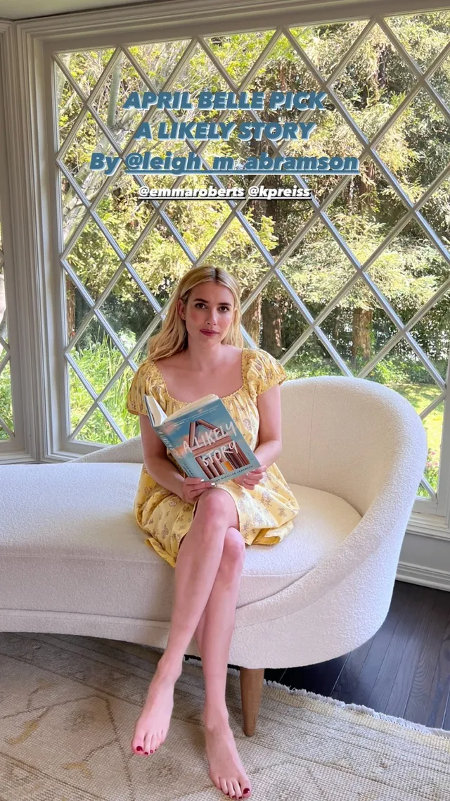 Emma Roberts sitting barefoot with a book in a yellow dress.
