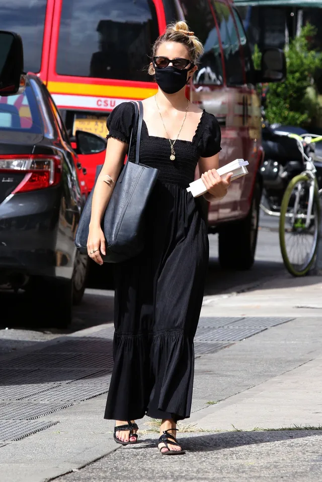 Dianna Agron walking with takeaway containers in a black dress.