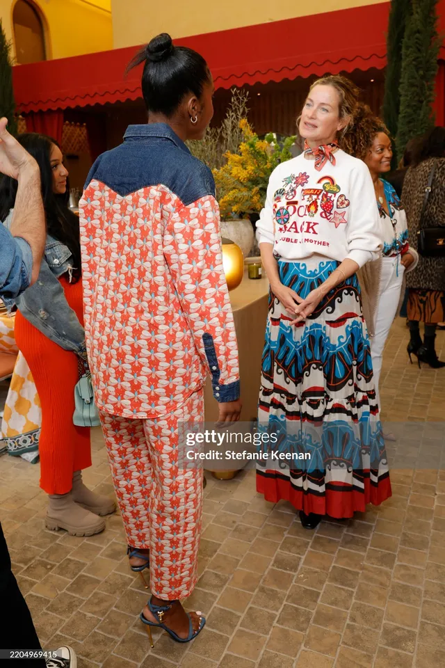 Carlacia Grant standing with a guest in a patterned suit and blue heels.