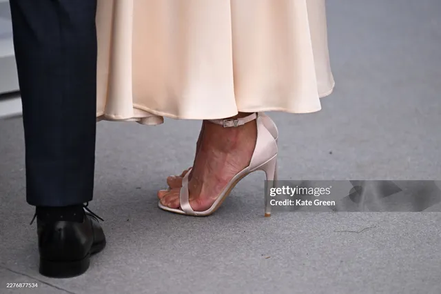 Alicia Vikander wearing pale heels beside another guest.