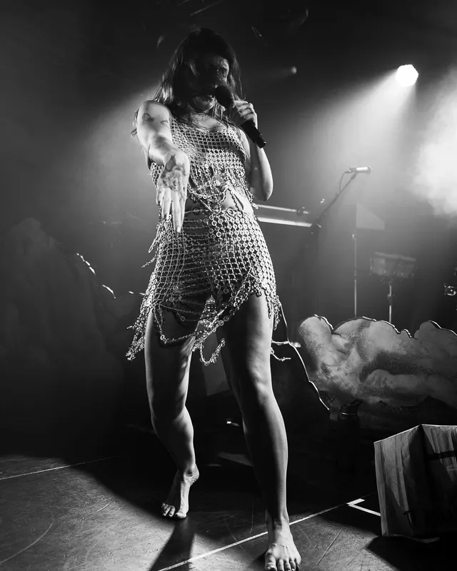 Tove Lo standing barefoot on stage in a monochrome photograph.