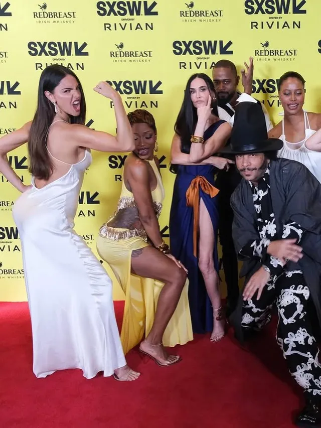 Eiza González posing with a group on a red carpet in a white dress.