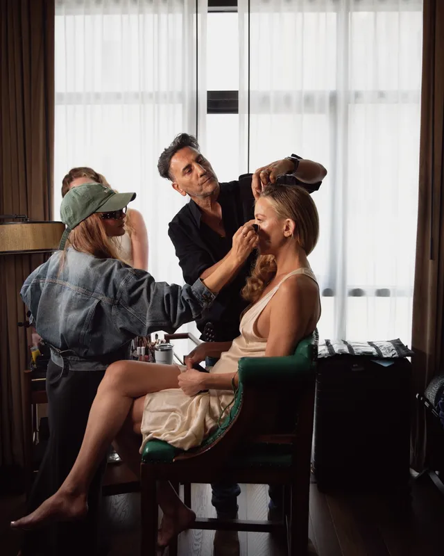 Kate Hudson sitting during makeup preparation with her legs crossed.