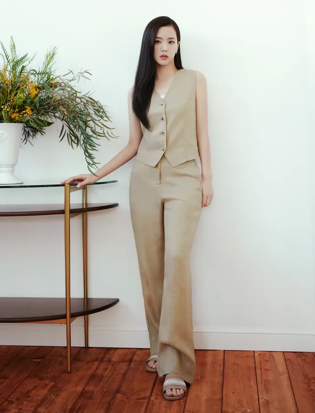 Jisoo standing in pale flat sandals and a light trouser suit.