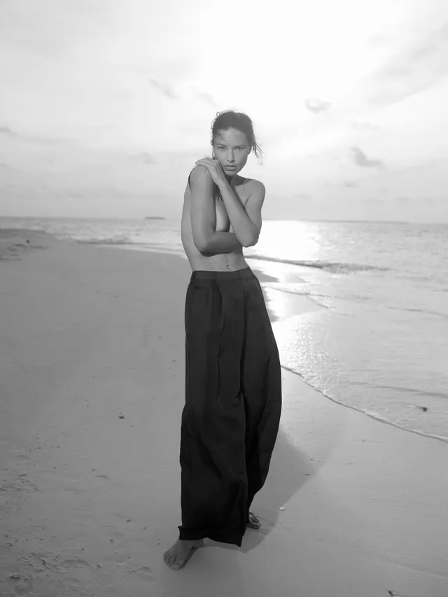 Adriana Lima a monochrome beach portrait in wide-leg trousers.