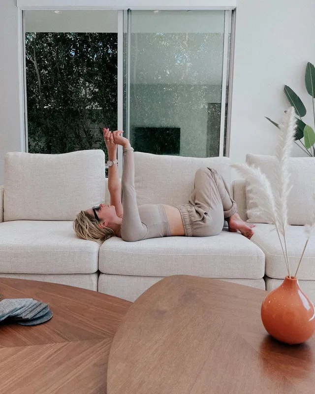 Ashley Benson reclining on a pale sofa in a casual outfit.