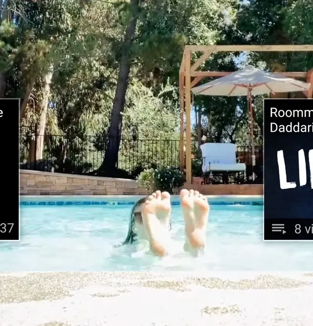 Alexandra Daddario raising bare feet beside a swimming pool.