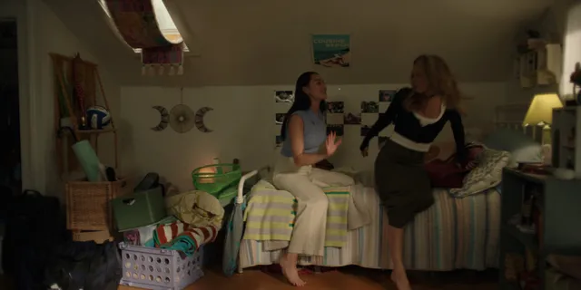 Lola Tung sitting beside another woman on a bed in a screen capture.
