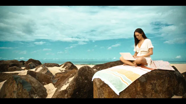 Alycia Debnam-Carey reading on rocks beside the sea during a screen scene.
