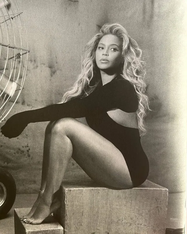 Beyoncé sitting barefoot in a monochrome fashion portrait.