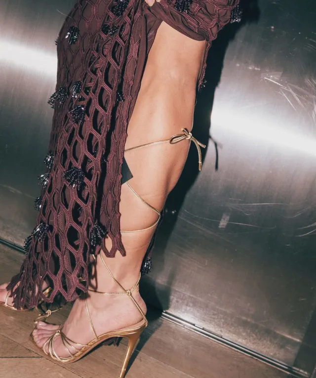 Sarah Shahi a close-up of lace-up heels with a dark dress.