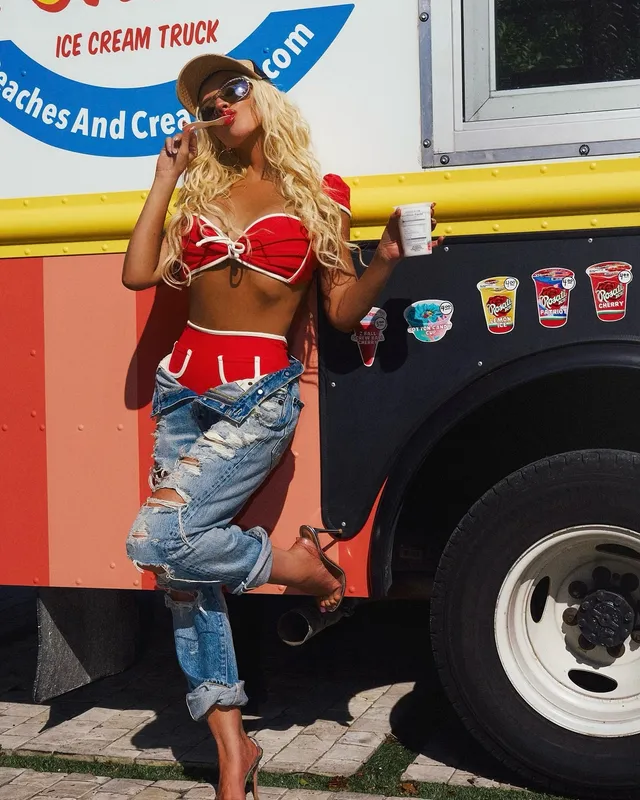 Christina Aguilera standing beside an ice-cream van in jeans and heels.