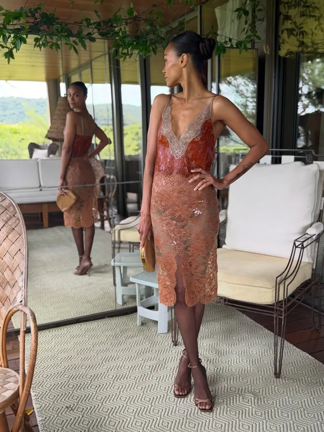 Zoe Saldaña standing indoors in a patterned dress.