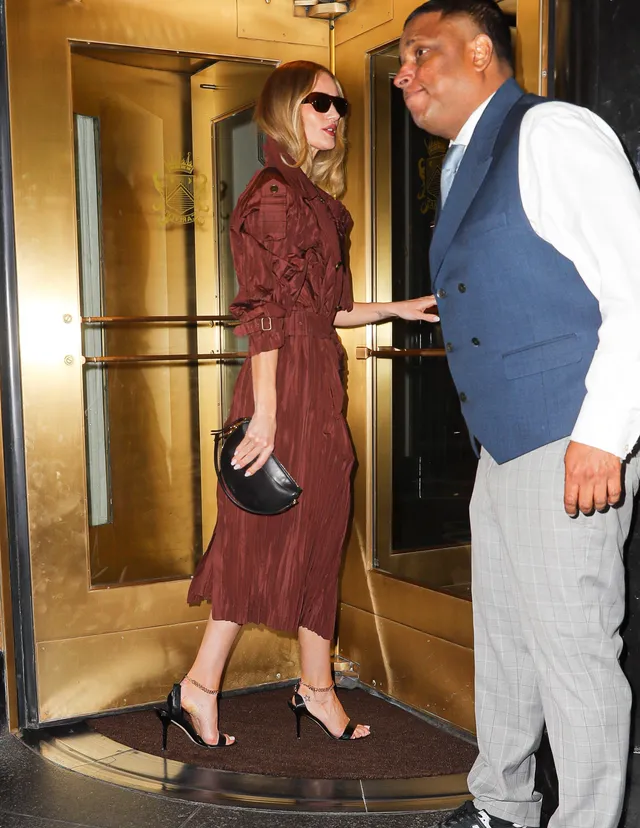 Rosie Huntington-Whiteley a burgundy dress and heels at an entrance.