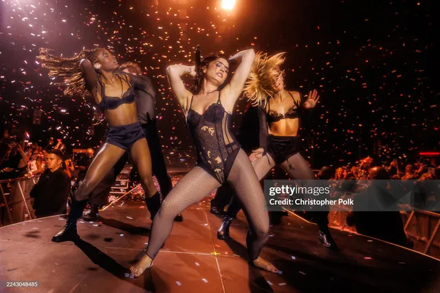 Demi Lovato performing on stage with dancers in gold heels.