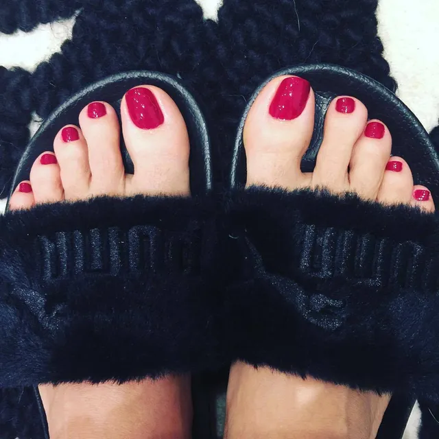Salma Hayek showing red nail polish in black slide slippers.