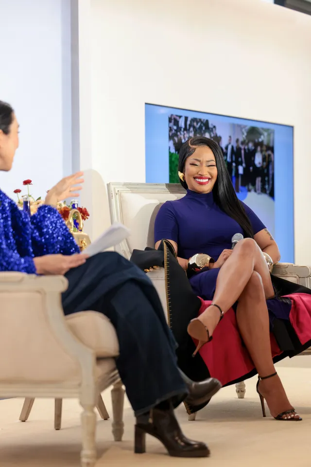 Nicki Minaj sitting on stage during an interview in strappy heels.