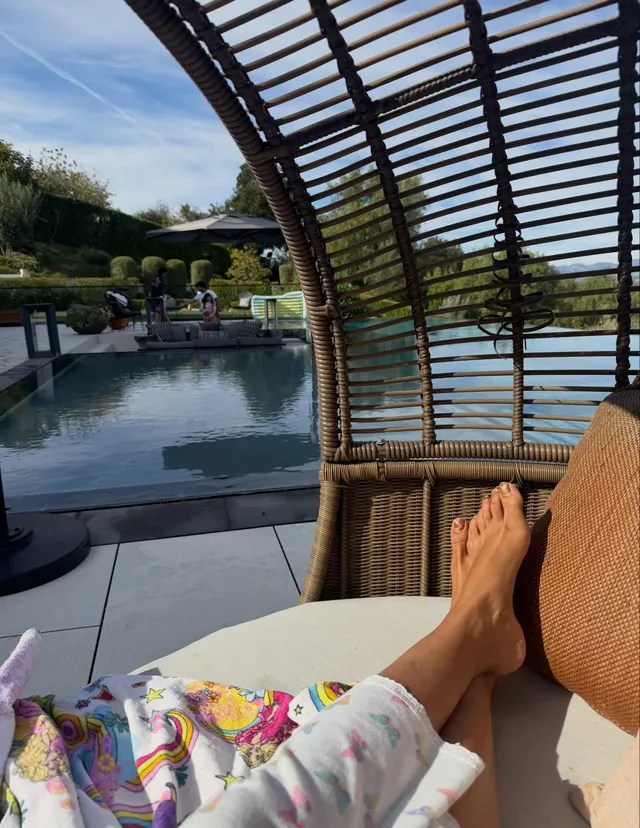 Priyanka Chopra Jonas resting her bare feet beside a pool beneath a shaded terrace.