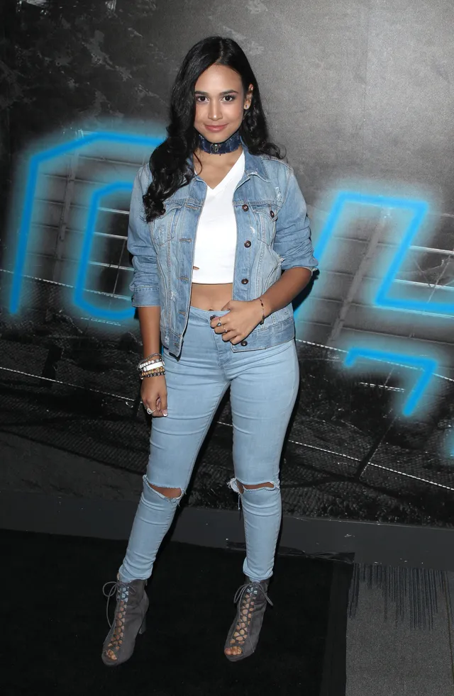 Emily Tosta wearing a denim outfit and open-toe heels.