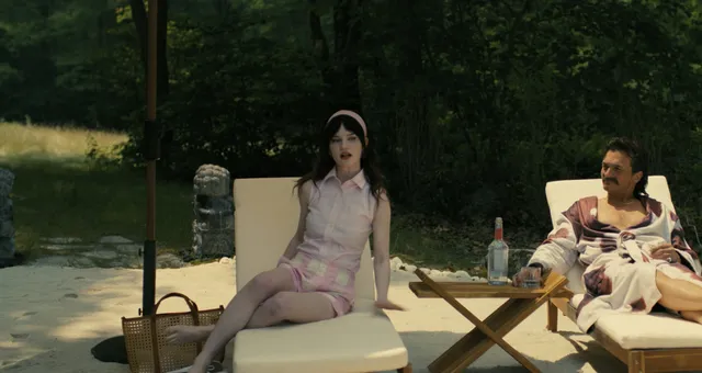 Sophie Thatcher sitting barefoot on a sun lounger beside a man.