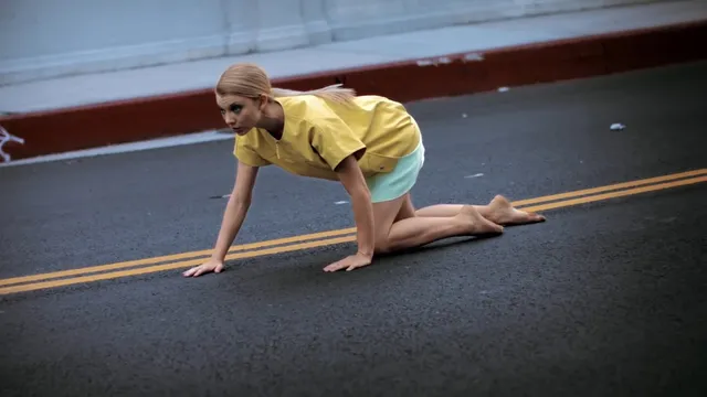Natalie Dormer crouching on a gym floor in an exercise scene.