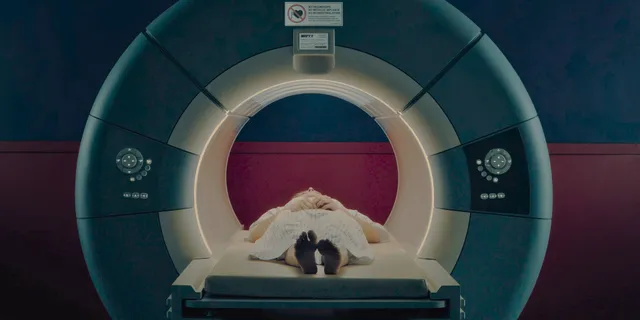 Chloë Grace Moretz lying in a medical scanner with bare feet visible.