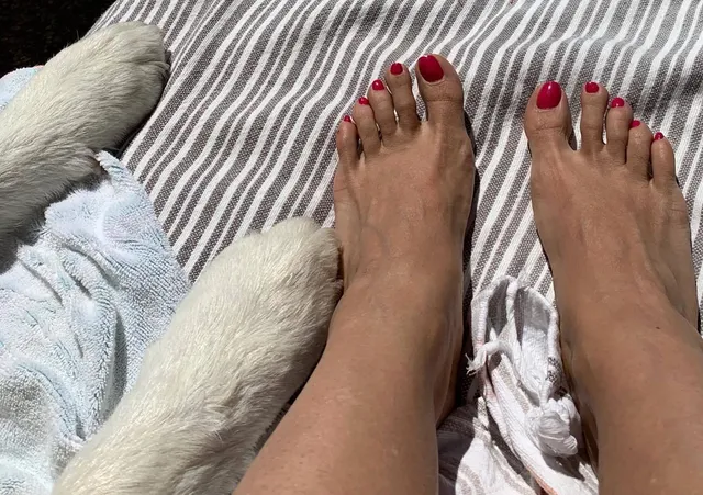 Salma Hayek showing red nail polish while relaxing on a striped cushion.
