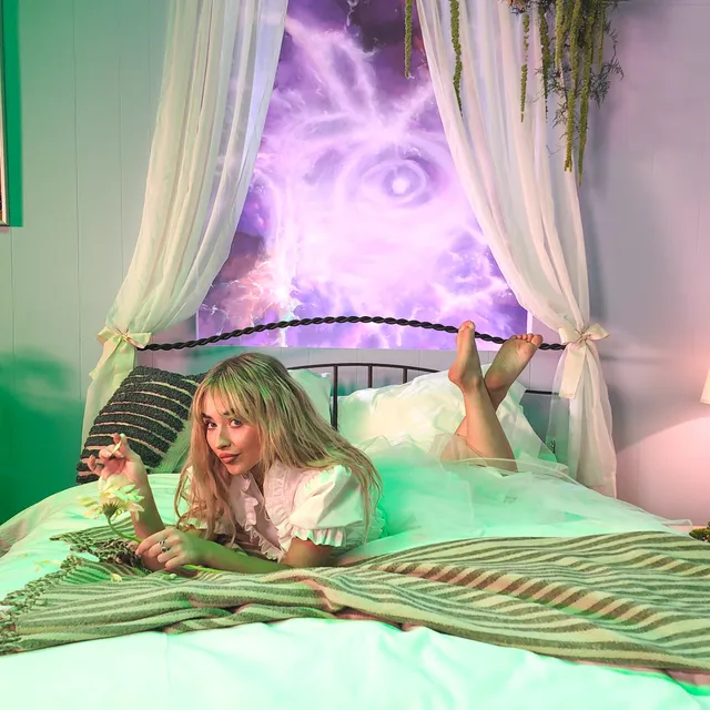Sabrina Carpenter: reclining barefoot on a bed in green light.