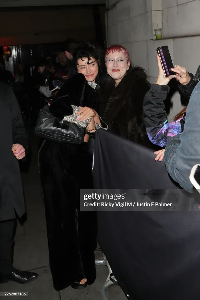 Odessa A'zion taking a photograph with a guest while wearing black heels.