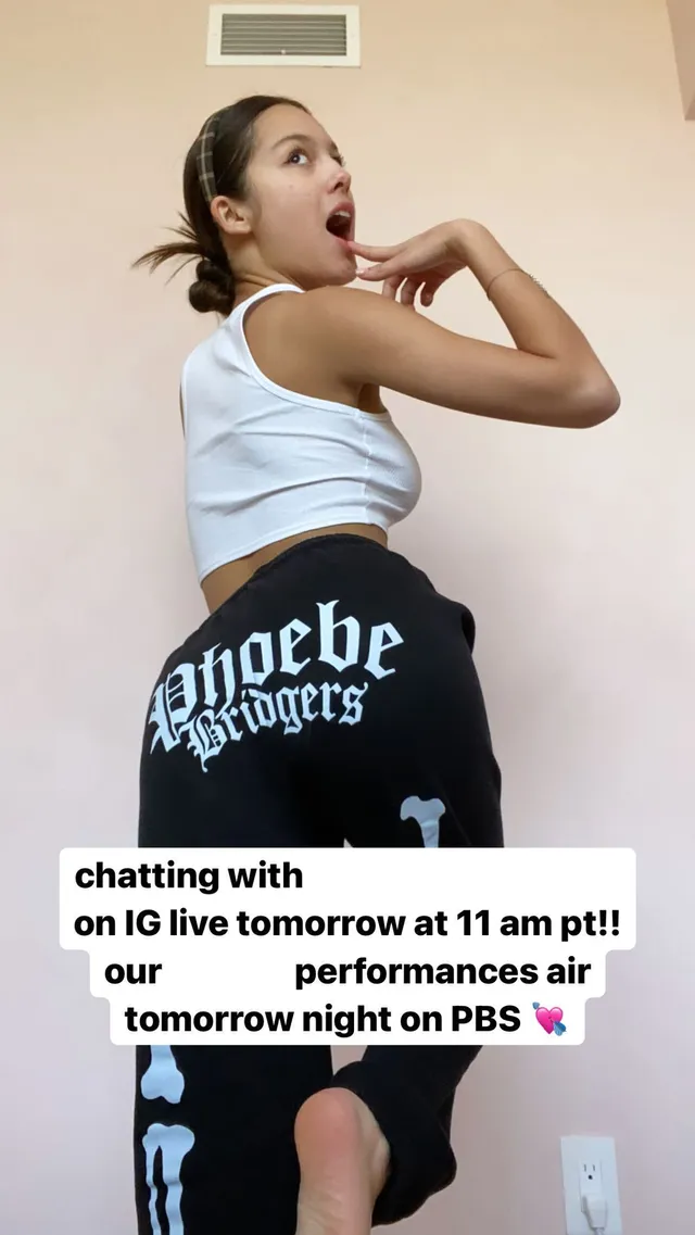 Olivia Rodrigo posing indoors in a white cropped top.